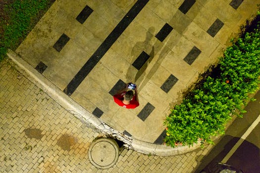 Aerial shot of a person in a red shirt walking on patterned pavement in Banten, Indonesia.