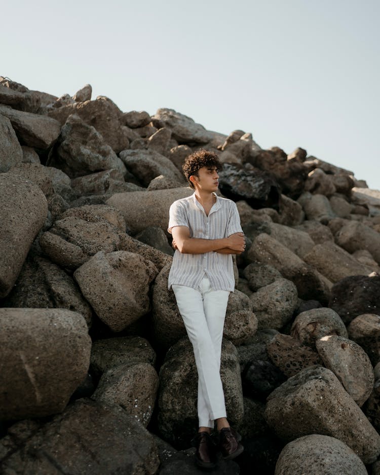 Man In Shirt Standing With Arms Crossed On Rocks