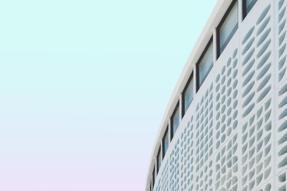 Modern building facade showcasing unique geometric patterns against a pastel sky.
