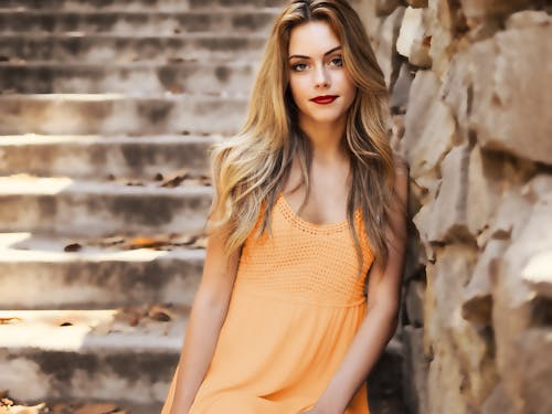 Free Woman Wearing Orange Dress Leaning on Brown Wall Near Stairs Stock Photo