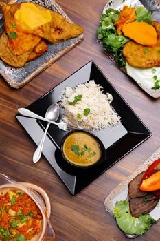 Authentic Pakistani meal with rice, curry, and assorted sides served on a wooden table.