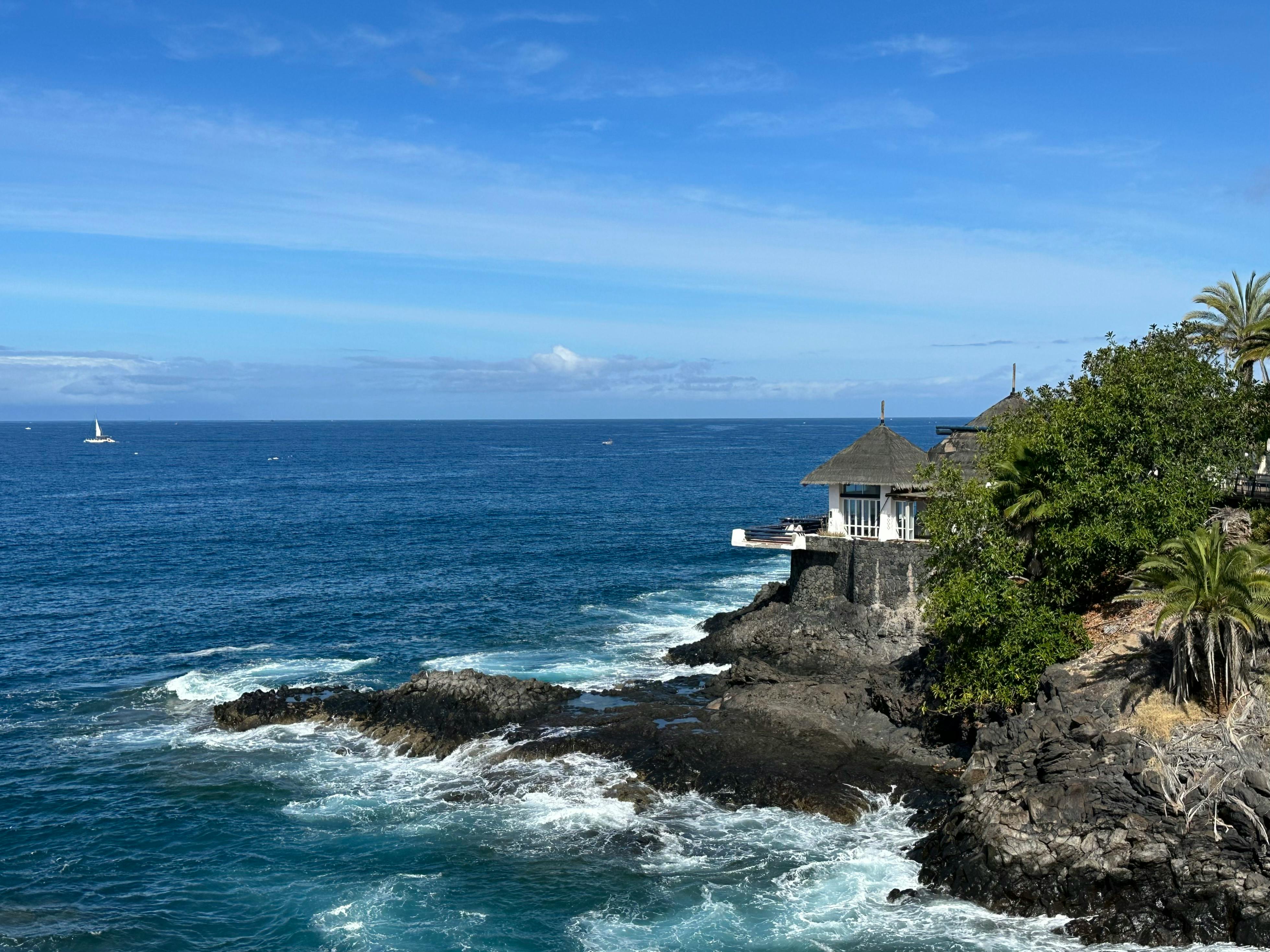 Free Beautiful coastline with waves crashing on rocks under a clear blue sky in Costa Adeje, Spain. Stock Photo