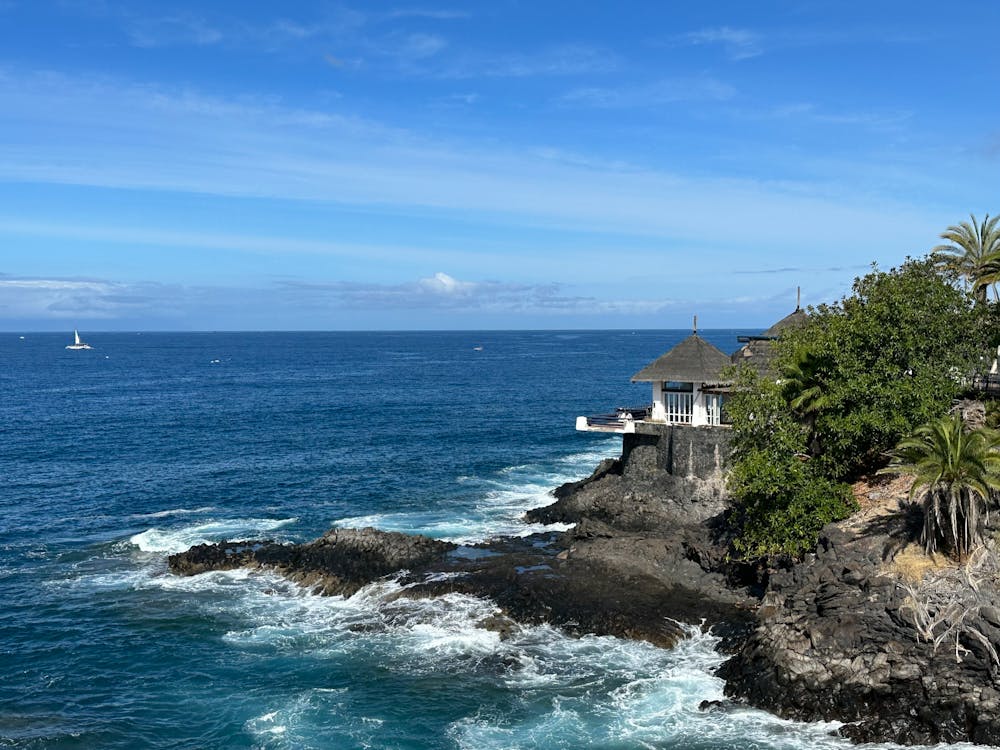 Free Beautiful coastline with waves crashing on rocks under a clear blue sky in Costa Adeje, Spain. Stock Photo