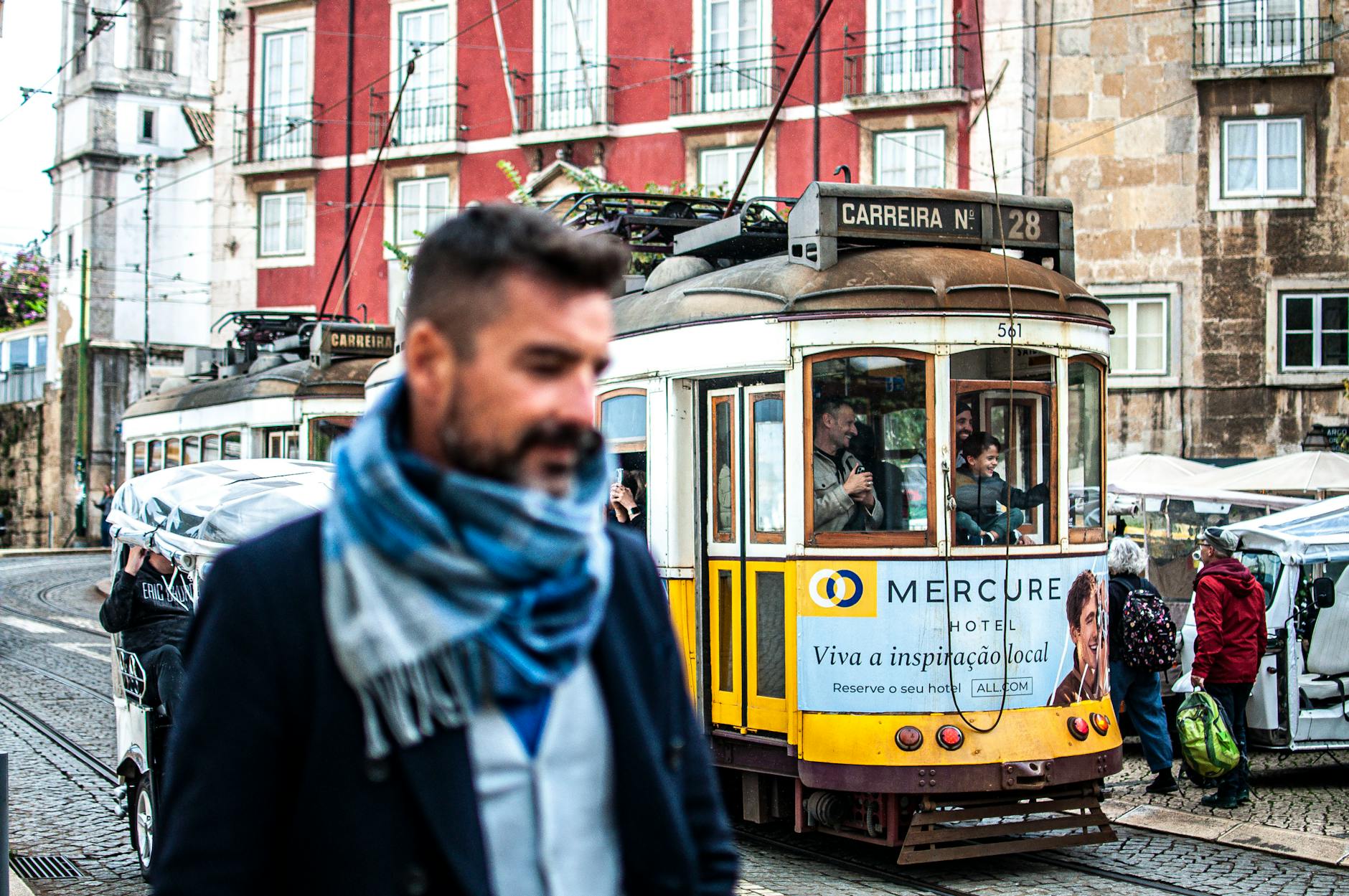 A vibrant street scene capturing a Lisbon tram and a passerby in a scarf, showcasing urban life.