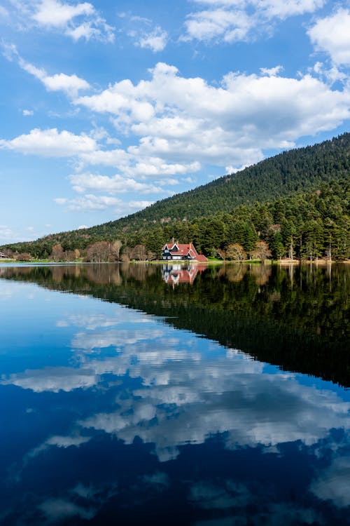 A lake with a house and mountains in the background