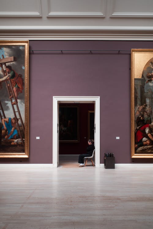 A person is sitting in front of two large paintings