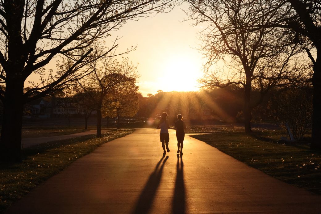 Two runners silhouetted on a park path at sunrise — photo by David Kanigan on Pexels