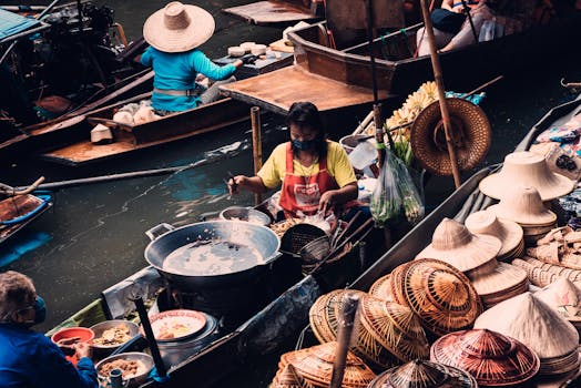 Traditional floating market in Bangkok featuring vendors selling hats and food from boats.