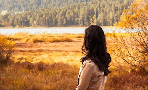 Woman Facing River Between Brown Fields