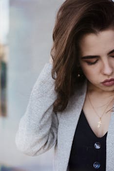 一个身穿休闲服的年轻女子体贴地轻抚头发，陷入沉思