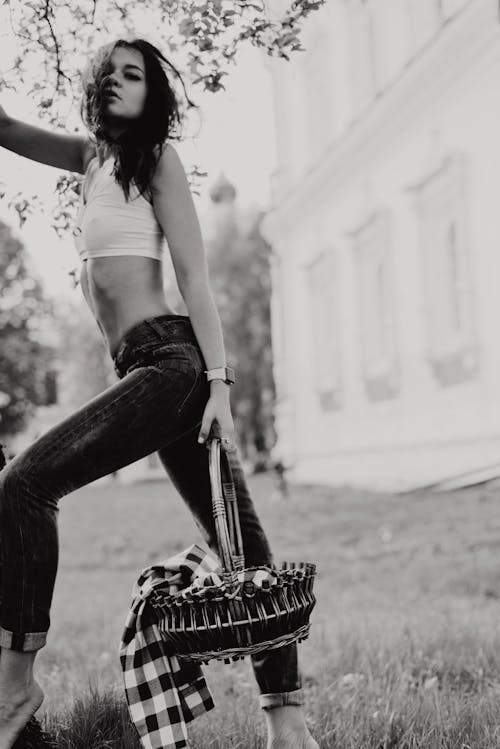 Grayscale Photo of Standing Woman in Crop Top Posing While Carrying Basket