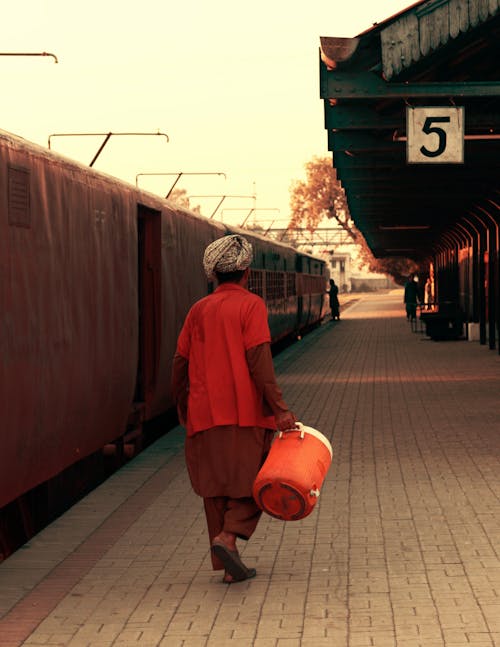 Person Holding Orange and White Jug