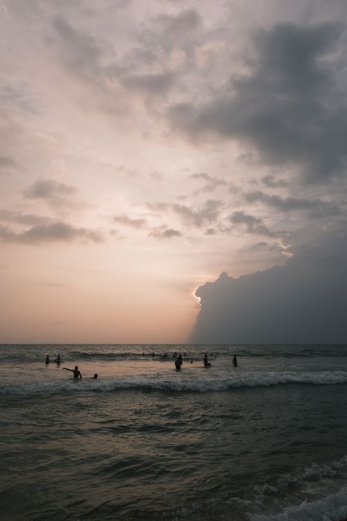 Free People enjoying a serene sunset at Varkala Beach, India, with dramatic clouds. Stock Photo