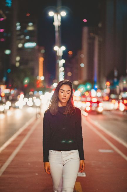 Elegant woman walking at night on an illuminated city street, captured during a moody urban photoshoot.