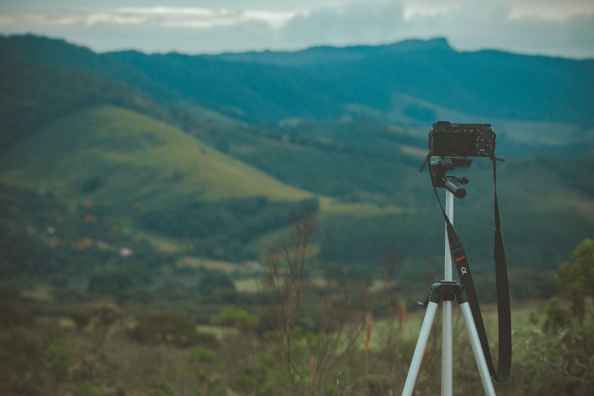 A camera on tripod capturing stunning mountain landscape at twilight.