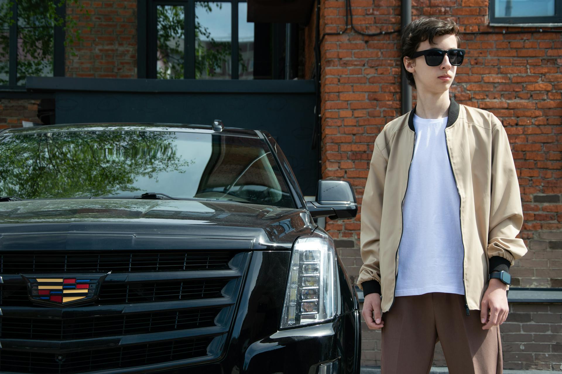 Brunette in Sunglasses and Jacket by Cadillac Escalade