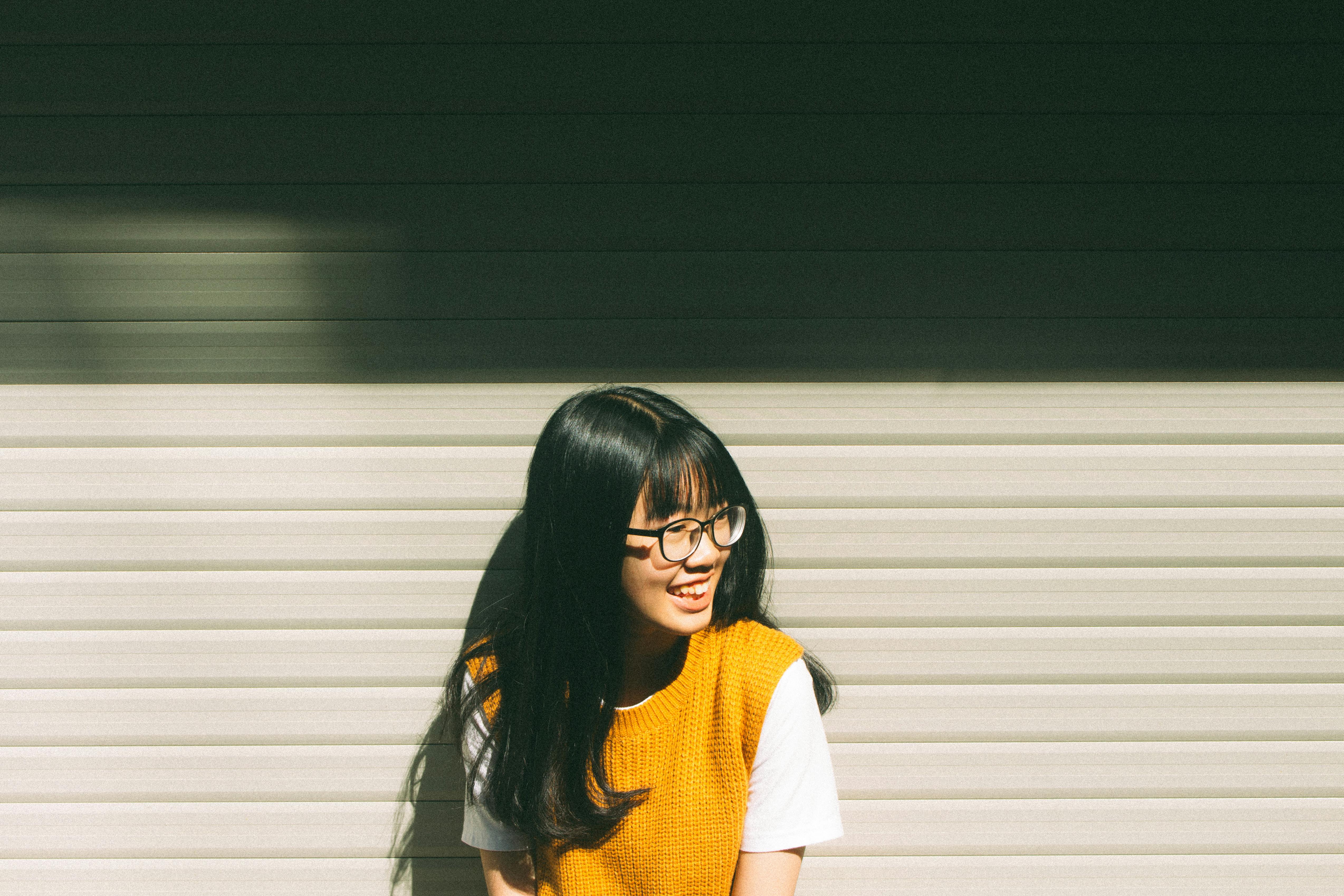 gratis Glimlachende Vrouw Die Op Grijze Muur Leunt Stockfoto