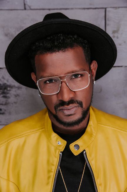 Portrait of a confident man in a yellow jacket and stylish eyewear, showcasing modern fashion.