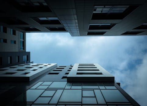 从低角度仰望多云天空下的现代摩天大楼，展现城市建筑设计