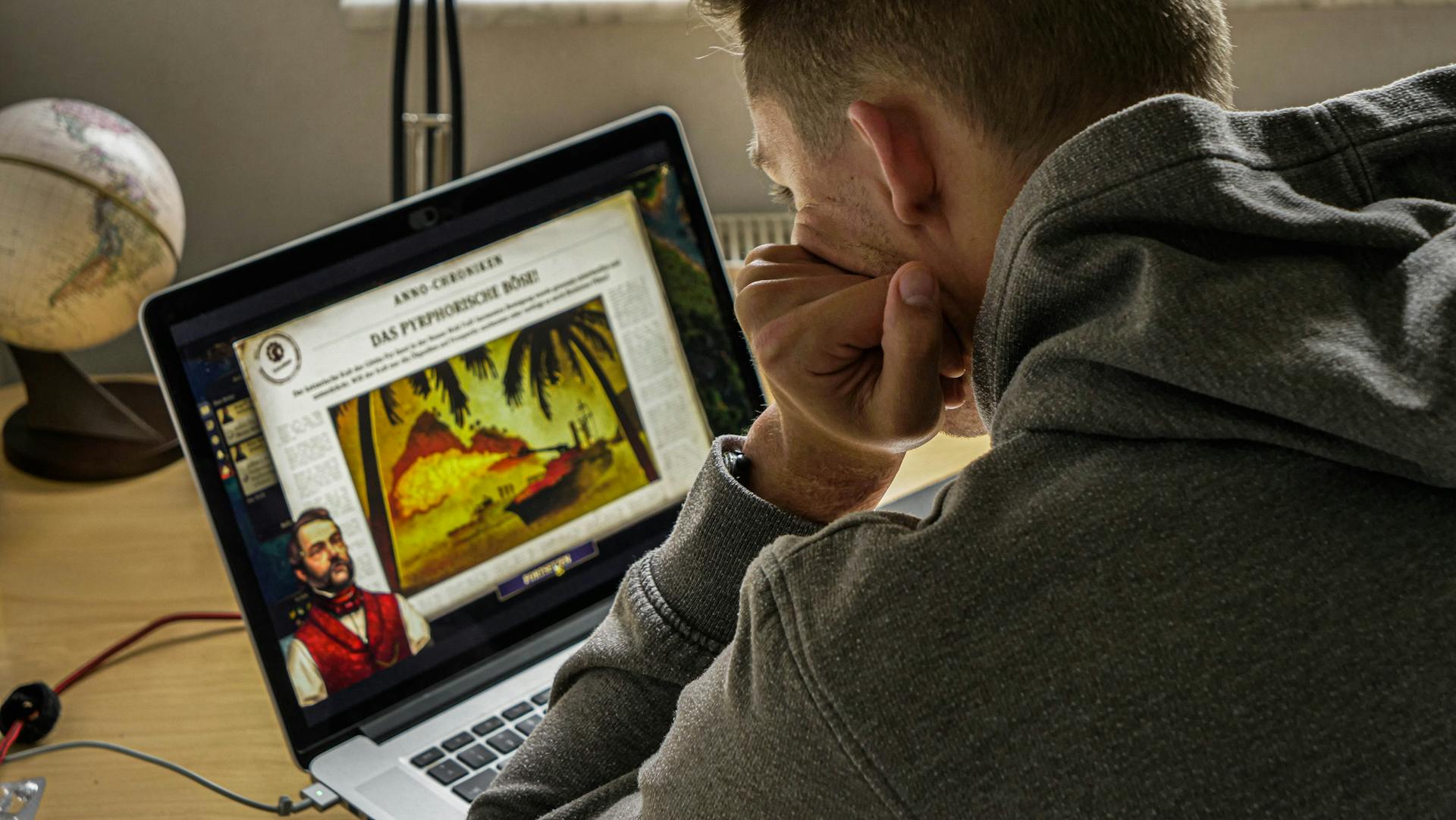 A man intently studies historical content on his laptop in a cozy indoor setting.