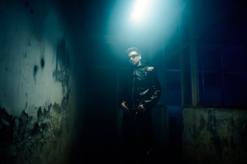 A man in a leather jacket standing in an abandoned building