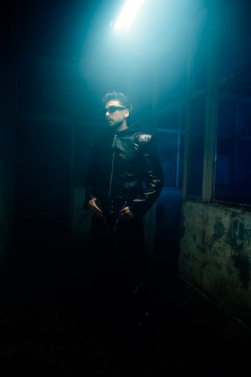 A man in a leather jacket standing in a dark room