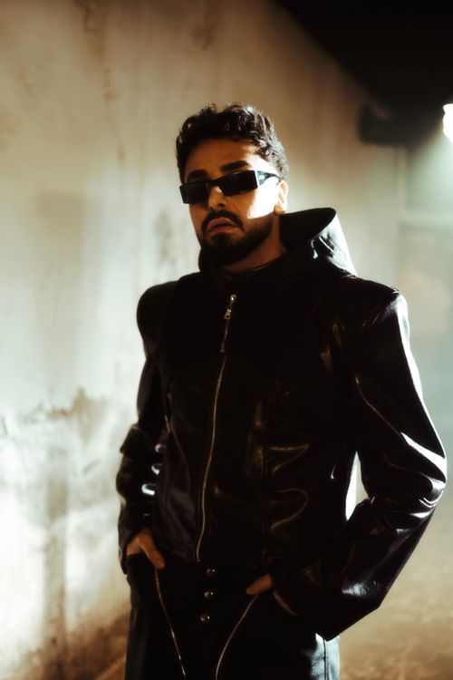 Free Portrait of a fashionable man wearing sunglasses and a leather jacket indoors with dramatic lighting. Stock Photo