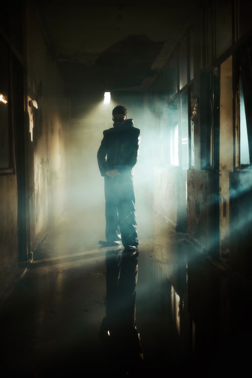 Free Eerie silhouette of a man in a smoky, dark corridor wearing a jacket and sunglasses. Stock Photo