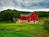 在威斯康星州郁郁葱葱的绿叶和多云的天空下，一座红色谷仓显得格外醒目