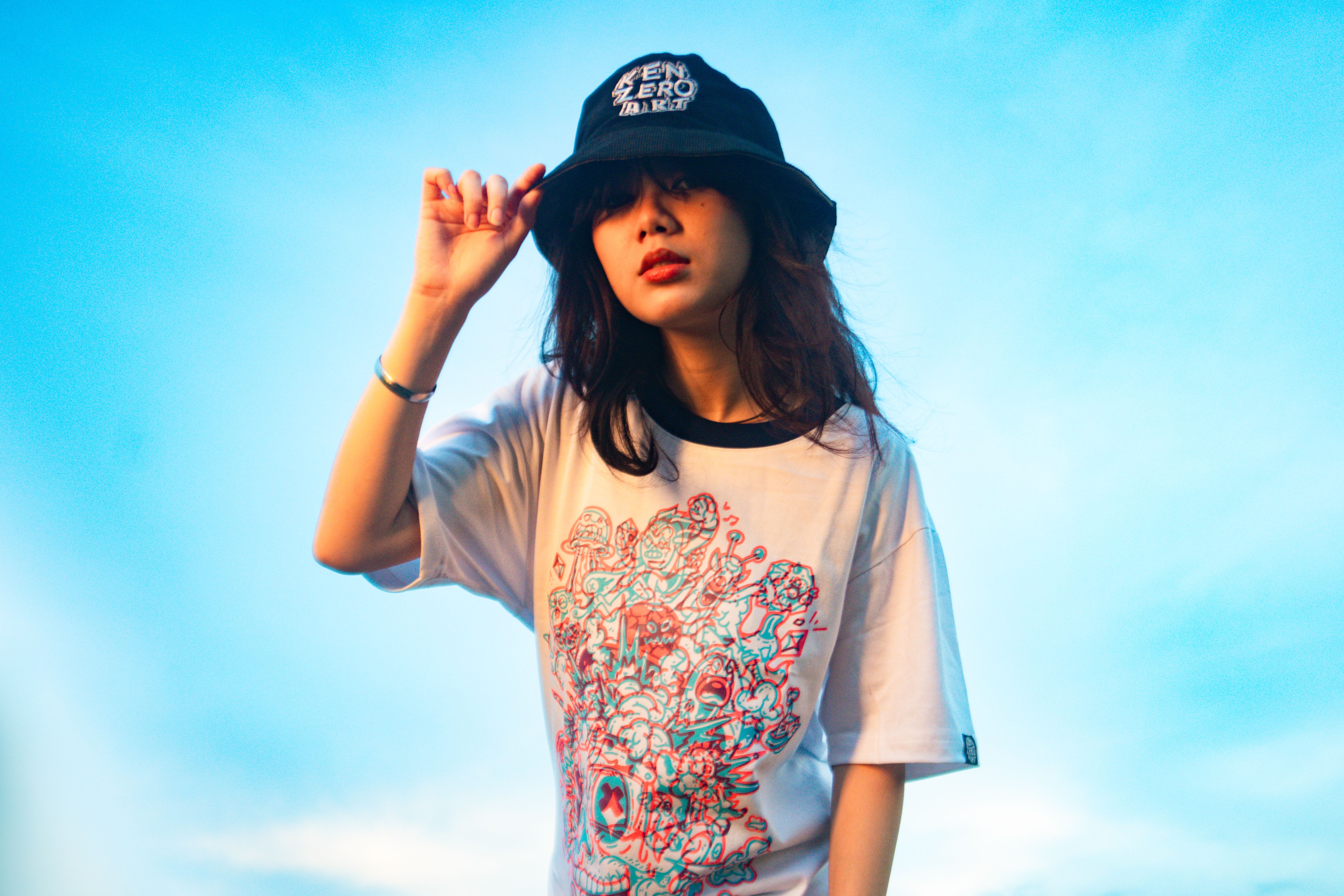 Stylish woman posing in hat against a clear blue sky.