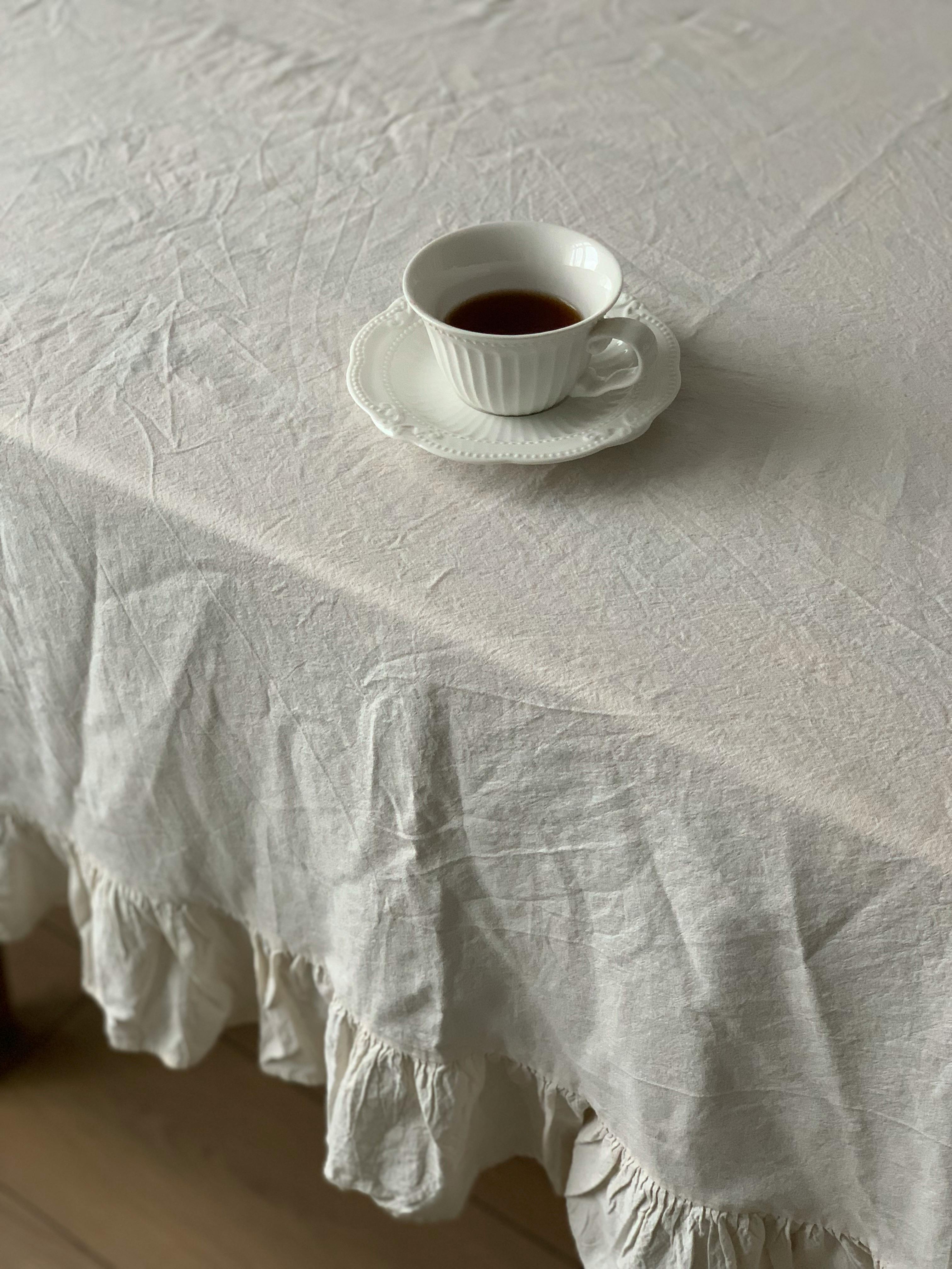 Simple white teacup on a textured tablecloth, offering a minimalist and cozy vibe.
