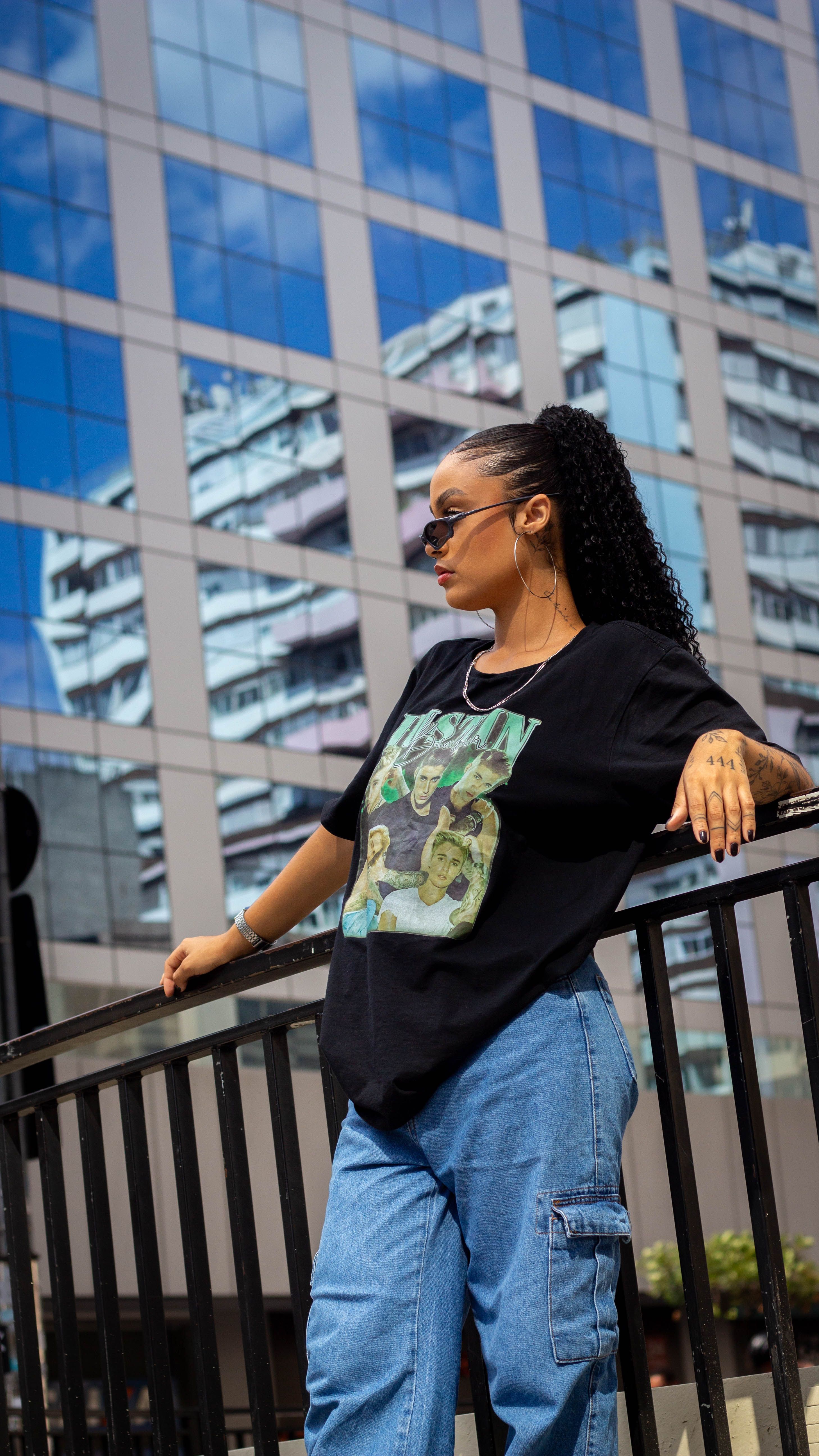 Stylish woman in urban setting with reflective skyscraper backdrop.