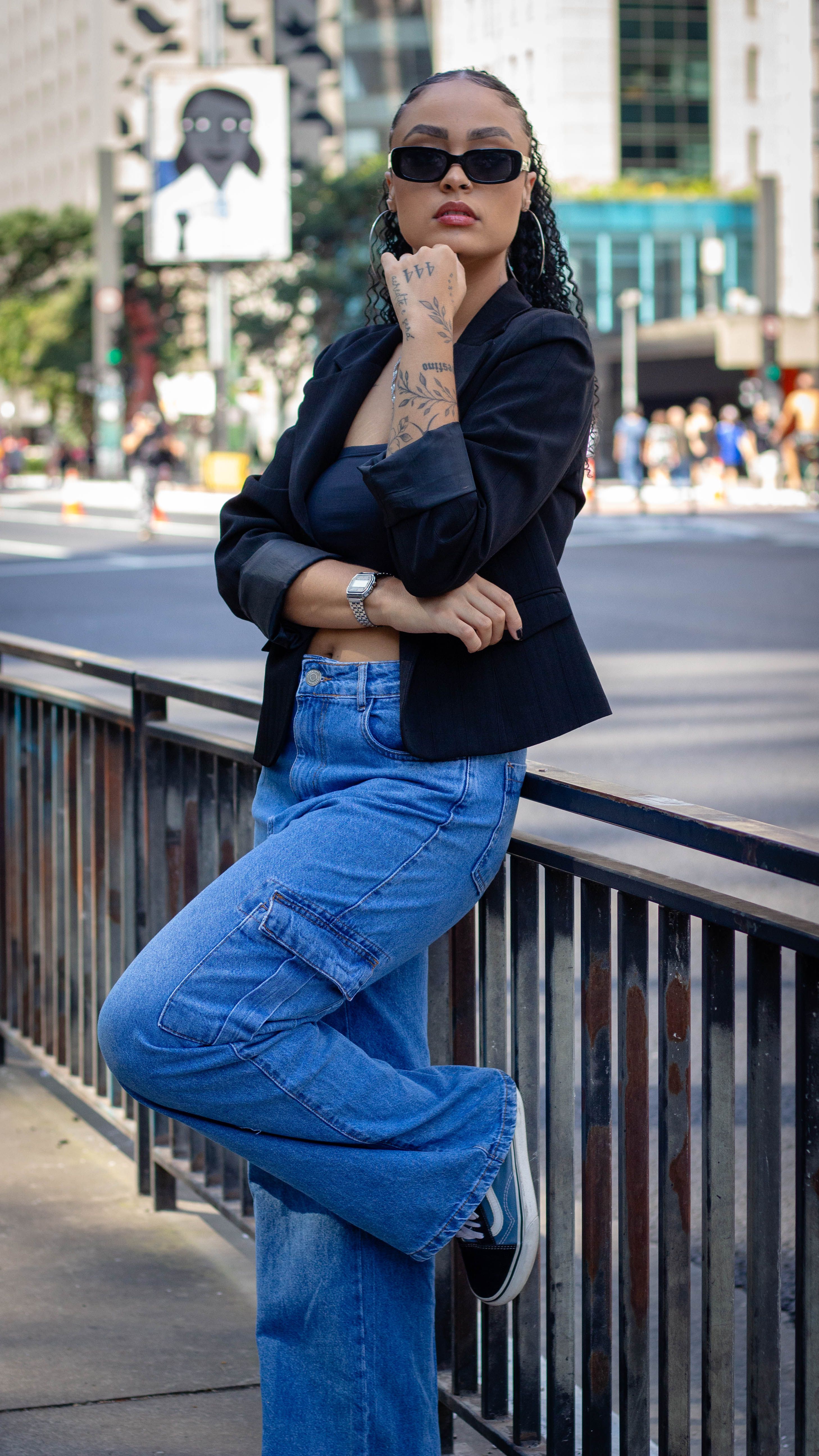 Mulher estilosa em denim e óculos de sol posa em ambiente urbano. Estilo de rua fashion.