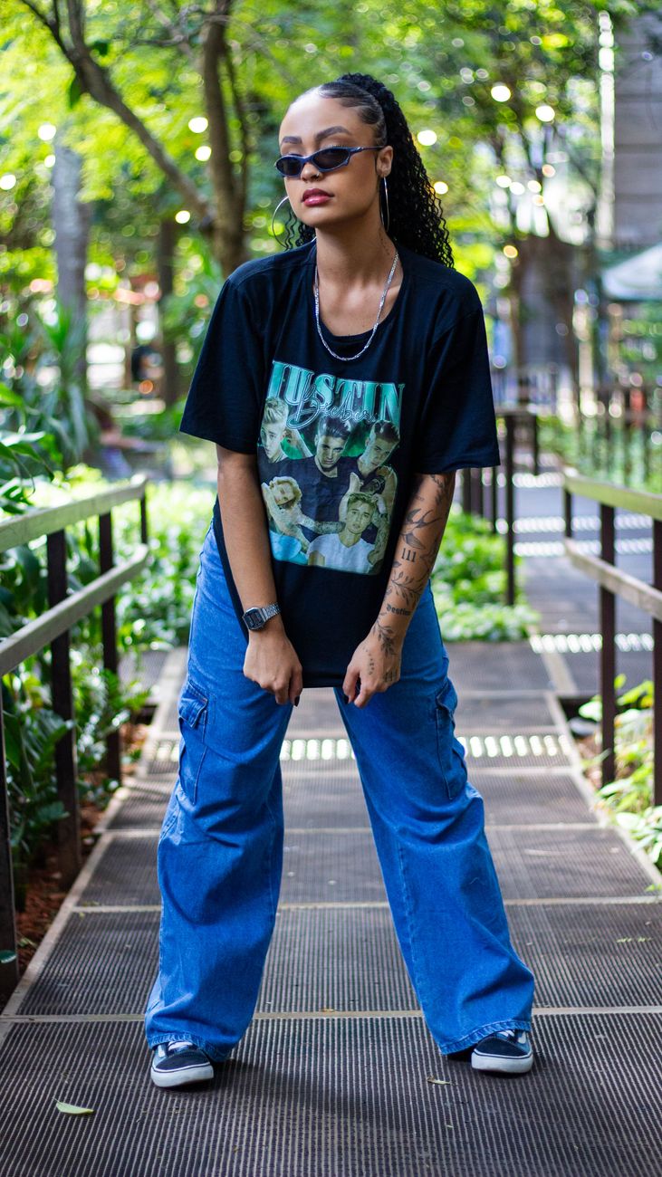 Mulher estilosa em óculos de sol e roupa descontraída posando em um ambiente urbano ao ar livre.