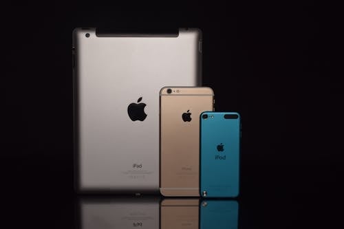 Free Space Gray Ipad, Gold Iphone 6, and Blue Ipod Touch Stock Photo