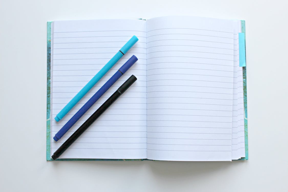 Gratis Notebook Terbuka Dengan Tiga Pena Aneka Warna Foto Stok