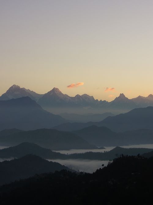 Free Serene view of a misty mountain landscape at sunrise, showcasing silhouettes and fog. Stock Photo
