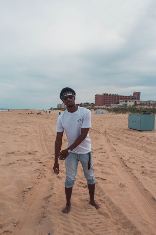 Free Man enjoying a casual walk on Ocean City beach with urban backdrop. Stock Photo