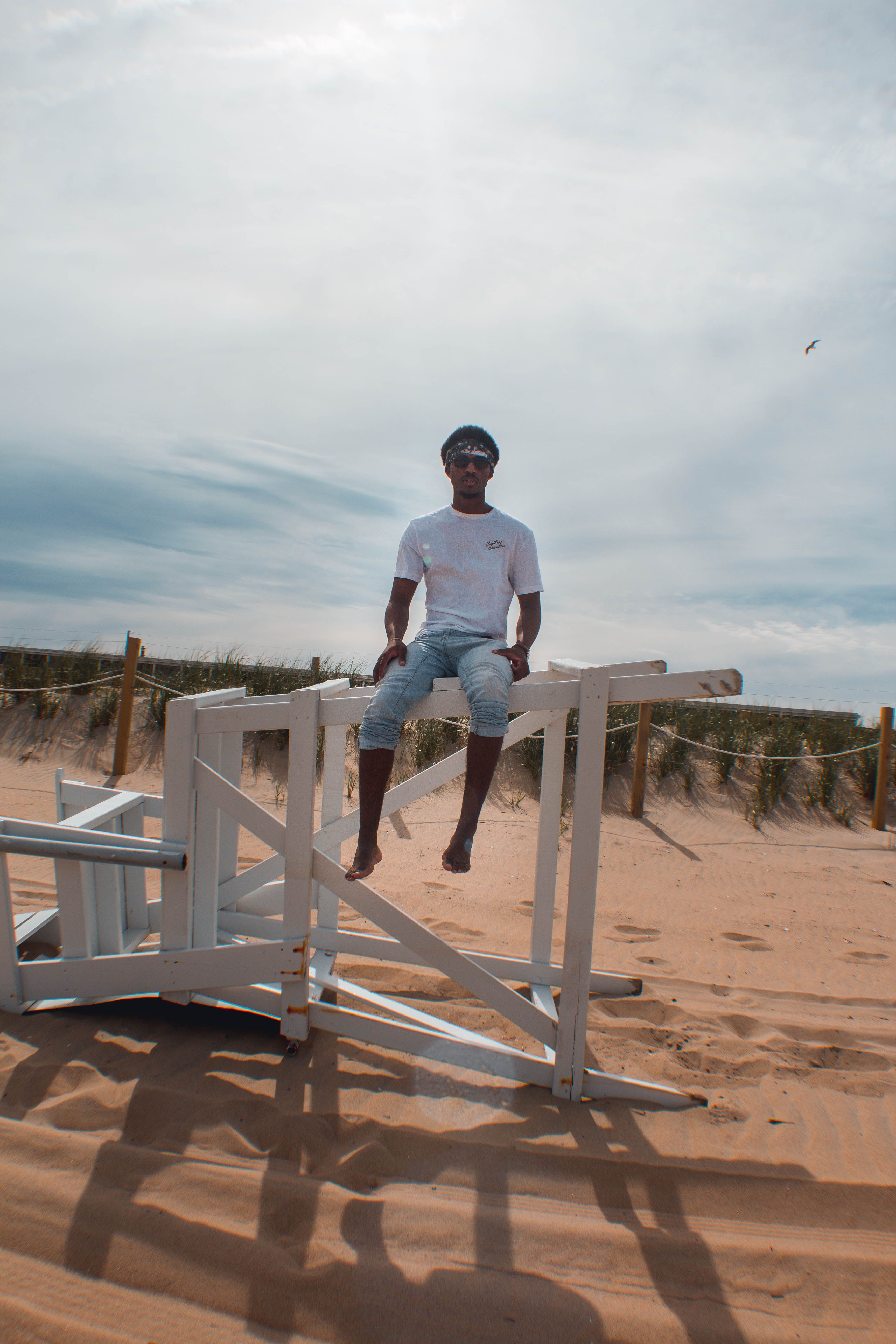 Back View Photo of Man Sitting on White Wooden Railing at The Beach ...