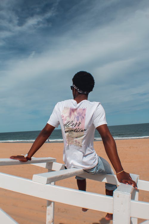 Vue Arrière Photo De L'homme Assis Sur Une Balustrade En Bois Blanc à La Plage