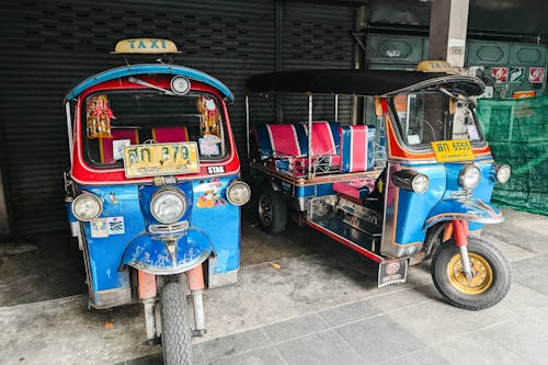 Two tuk - tuks parked next to each other on the street