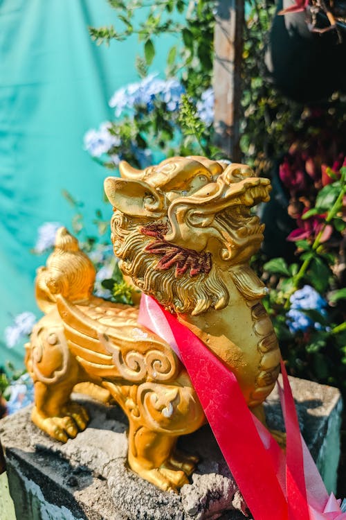 A golden statue of a chinese dragon with a red ribbon