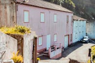 阳光明媚的日子里，粉红色的房屋风景如画，展现出乡村的魅力和古雅的建筑风格