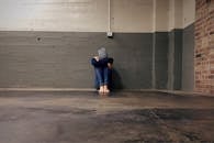 一个人坐在空房间里，面对混凝土墙，传达出孤独和绝望