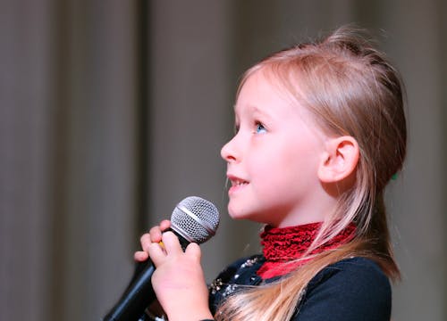 Kostenlos Mädchen, Das Schwarzes Dynamisches Mikrofon Hält, Während Es Oben Schaut Stock-Foto