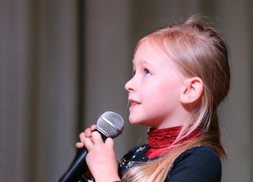 Mädchen, Das Schwarzes Dynamisches Mikrofon Hält, Während Es Oben Schaut