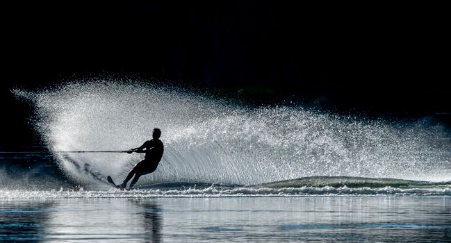 Silhouette of a waterskier creating a splash under the sun in Wenatchee, WA.