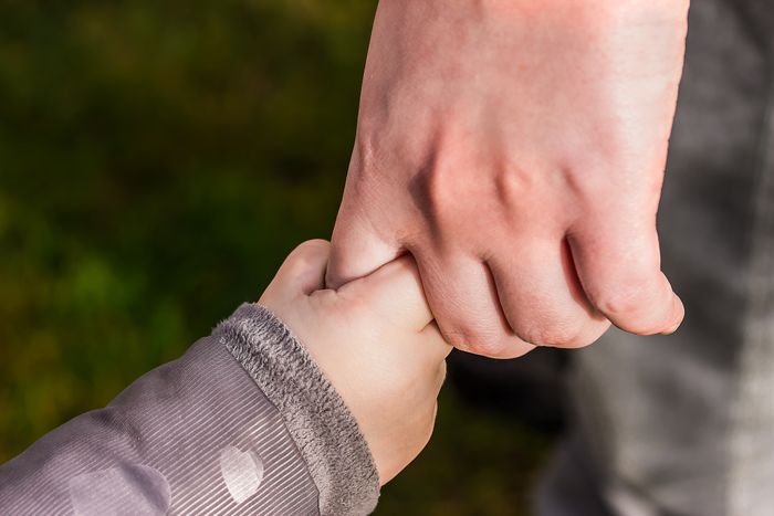 Child holding a parent's hand outdoors