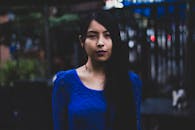 一个穿着蓝色连衣裙的女人在户外沉思，表情喜怒无常