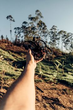 A person holding a drone outdoors, showcasing modern technology against a rural backdrop.